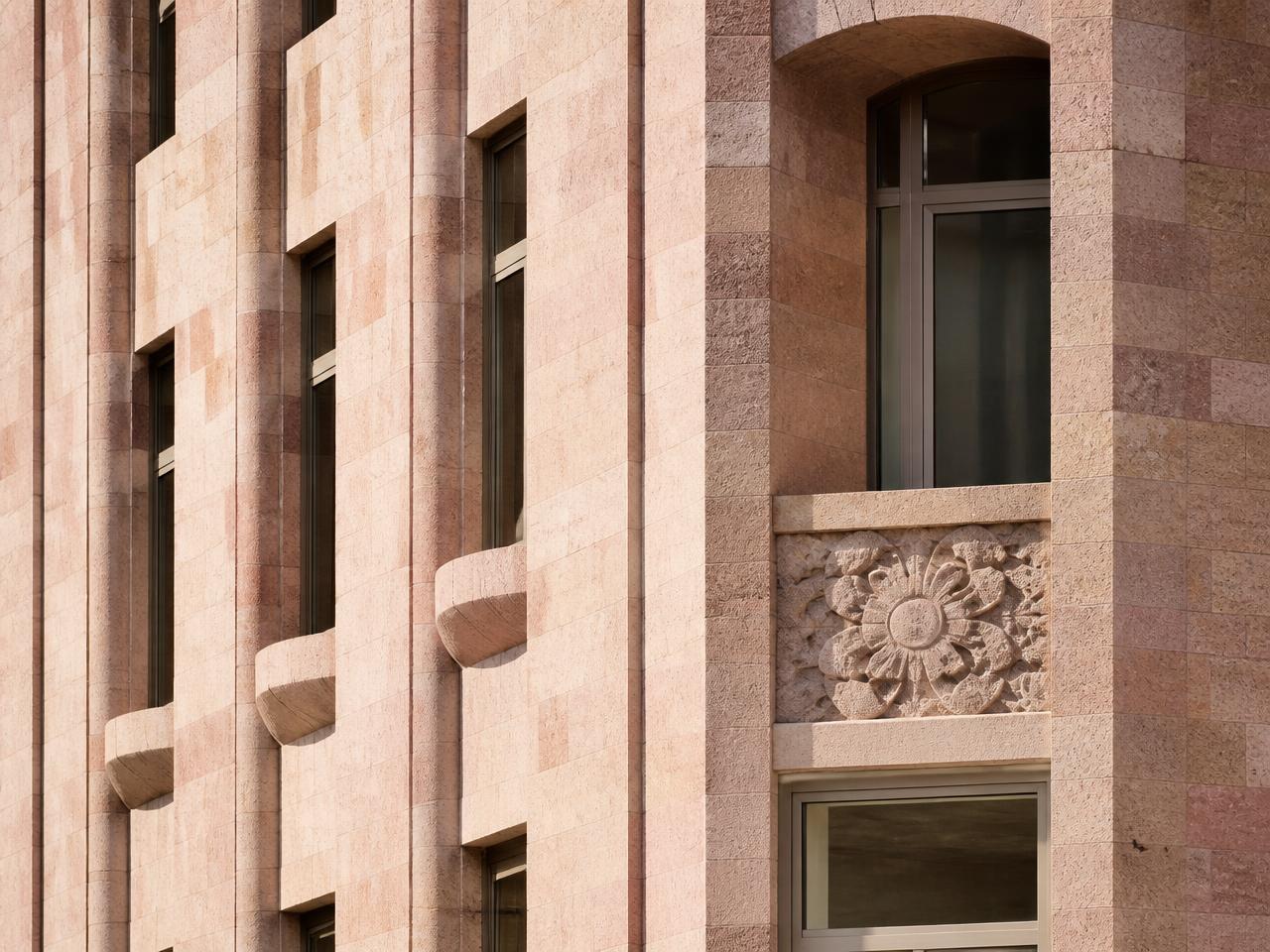 Close crop of a contemporary Yerevan façade in warm Armenian tuff stone with repeating window bays